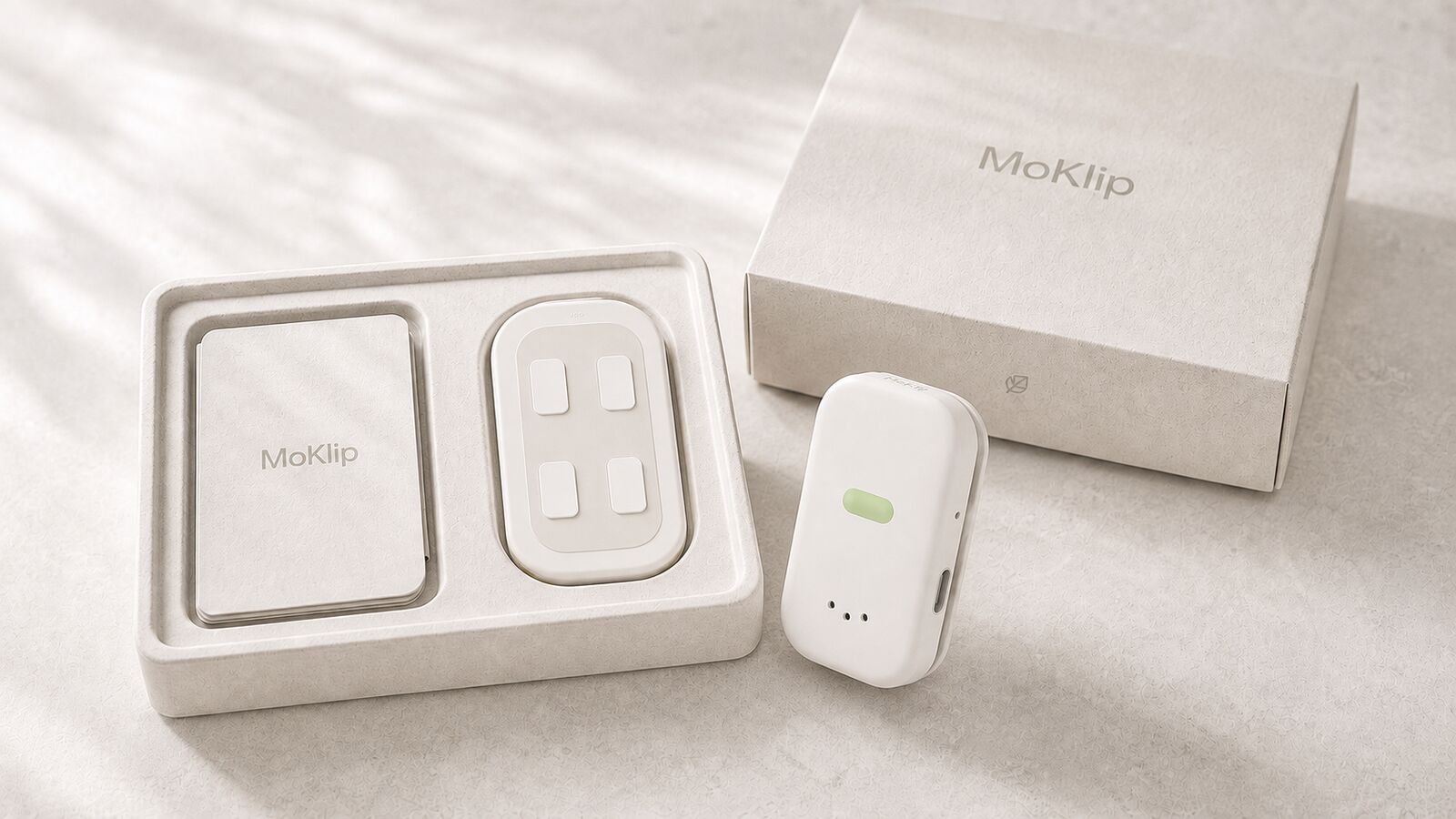 Conceptual MoKlip packaging with an open tray, quick-start guide, closed box, and the device standing beside it
